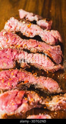 Beautiful ribeye steaks on a wooden board, perfectly seared with a golden crust and rare interior. Ready to slice and serve. Ideal for gourmet dining Stock Photo