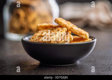 Crunchy salted crackers in bowl on a black table. Stock Photo