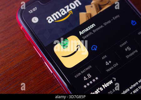 Amazon shopping app displayed on iPhone with install icon, user ratings, and ranking shown on wooden background surface. Stock Photo