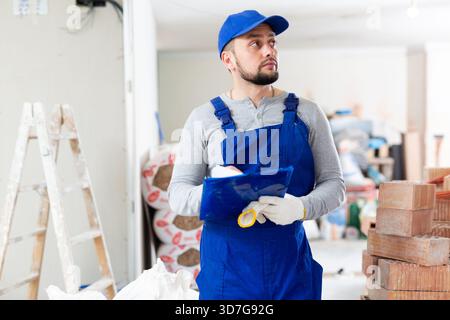 Foreman reading papers on indoor construction site Stock Photo