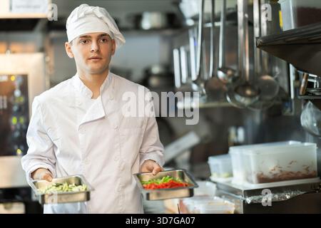 Young male chef prepares dish in restaurant kitchen Stock Photo