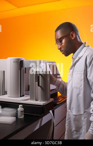 Young black man using electrochemiluminescence technology equipment in healthcare scientific laboratory, New Jersey, USA Stock Photo