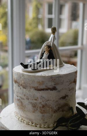 A wedding cake with a figurine of a man and woman on a sled. The man is laying down and the woman is standing up Stock Photo