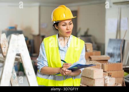Woman making notes on indoor construction site Stock Photo