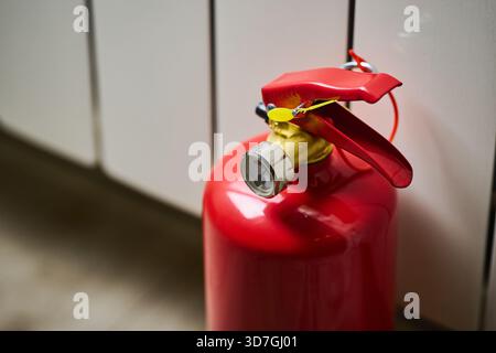 A red fire extinguisher is resting on the floor. Stock Photo
