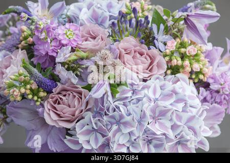 A pastel-toned arrangement featuring Rosa, Hydrangea macrophylla, Veronica spicata, and Clematis blossoms in shades of lilac, lavender, and blush pink Stock Photo
