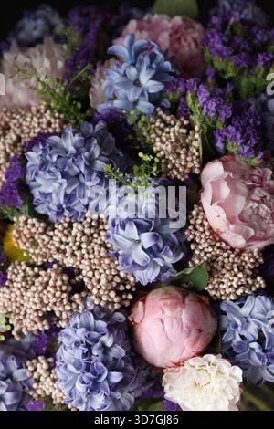 A dreamy floral composition combining blue Hyacinthus orientalis, pale pink Paeonia lactiflora peonies, and violet Limonium sinuatum (statice) Stock Photo