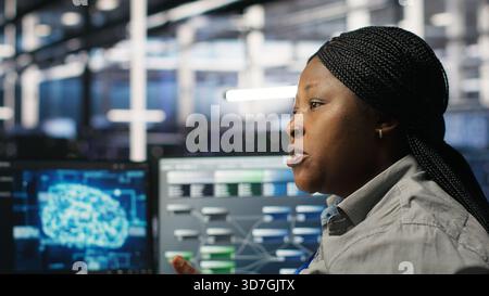 Data center engineering team deploying AI solutions optimizing gear. Server hub teamworking colleagues working together, using artificial intelligence to minimize systems downtime, camera B Stock Photo