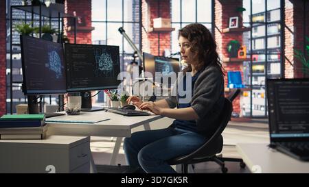 IT technician writing code and debugging on artificial intelligence neural networks computerized brain model. Female tech support doing checkup on AI systems, cloud computing. Camera A. Stock Photo