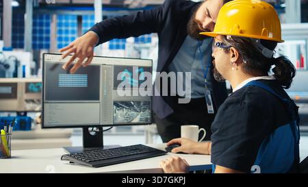 Photovoltaics factory manager shows engineer improvements to be made of robot arms manufacturing solar panels. Man shows technician upgrades needed after inspecting solar plant machinery, camera A Stock Photo