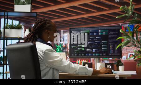 Teleworking programmer using computer for artificial intelligence computing through self learning algorithms. Remote worker working with AI deep neural networks on desktop PC, camera A Stock Photo