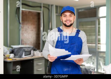 Foreman reading papers on indoor construction site Stock Photo