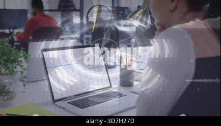 Displaying silver laptop showing spreadsheet at office desk, with woman in dark top, HUD overlay Stock Photo