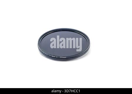 A dark, black-rimmed 77mm circular polarizing (CPL) camera filter, isolated on a clean white studio background. Stock Photo