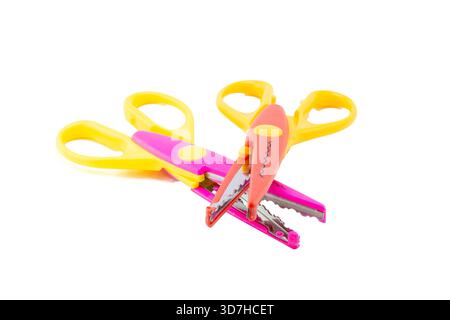 Two colorful decorative pattern-cutting craft scissors, one pink and one red, with yellow handles, isolated on white. Stock Photo