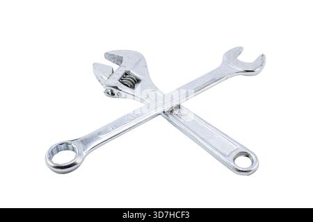 An adjustable wrench and a combination wrench, both chrome-plated, crossing each other on a white background. Stock Photo