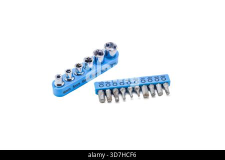 Small chrome socket and screwdriver bits arranged in blue plastic holders, isolated on a clean white background. Stock Photo