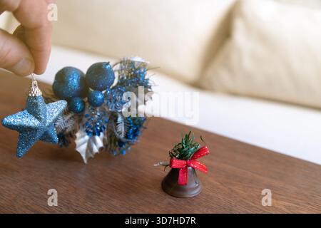 Hand decorating for holidays, placing a blue star and other festive elements on a wooden table Stock Photo