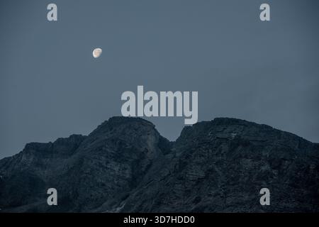 Moon Begins To Set Over Rocky Ridge In Glacier National Park Stock Photo