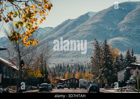Snowy mountain view from a main street with cars and fall foliage trees. Banff, AB Stock Photo