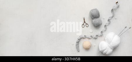 Yarn balls, scissors, buttons, measuring tape and knitting accessories on light background with space for text Stock Photo