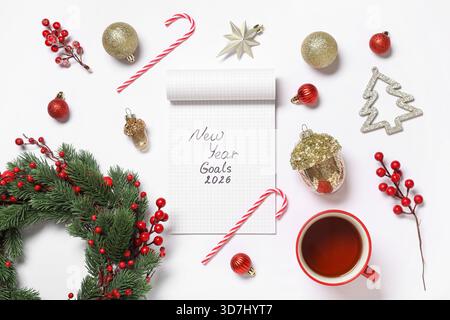 Notebook with text NEW YEAR GOALS 2026, Christmas decor and cup of tea on white background Stock Photo