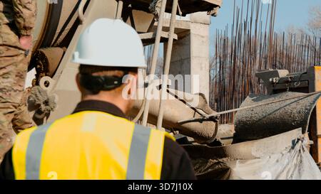 A construction worker in a high-visibility vest is working at a building Stock Photo