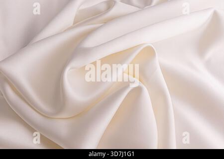 Elegant soft waves of satin fabric in cream, champagne. exquisite delicate material, texture. wedding concept. Festive background. layout for design. Stock Photo