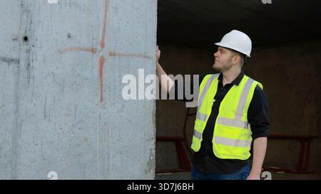 A construction worker inspects the wall of a building on a construction site. Stock Photo
