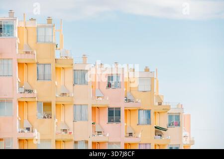 Stepped architecture of a summer holiday resort building with balconies and apartments painted in soft pastel pink and yellow Stock Photo