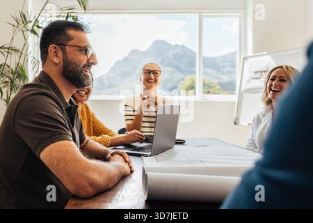 Group of diverse architects working together in a well-lit modern office environment with a scenic mountain view. Stock Photo