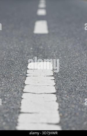 Vertical asphalt background with white dashed lines on the road leading forward into the future Stock Photo