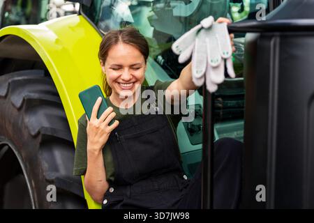 Candid woman next to tractor in farming lifestyle scene Stock Photo