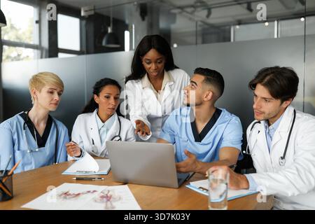 Puzzled doctors discussing medical cases, using laptop Stock Photo