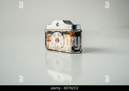 Rusted vintage subminiature camera with pinhole lens on a reflective white surface Stock Photo