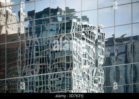 Reflection of downtown Montreal skyscrapers distorted in the glass facade of a modern building, creating an abstract urban pattern Stock Photo