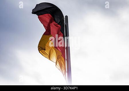 German flag waving in windy weather against an overcast sky. Diplomacy and Relations Stock Photo