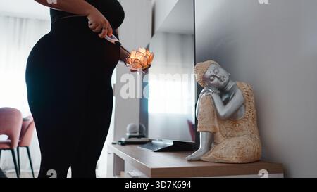 Pregnant woman holding lotus lamp near belly, practicing mindful self care Stock Photo