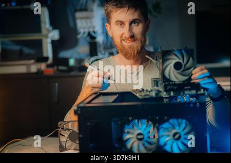 system administrator installing motherboard into system unit, assembling PC of different accessories or components, close-up view of hands, computer r Stock Photo