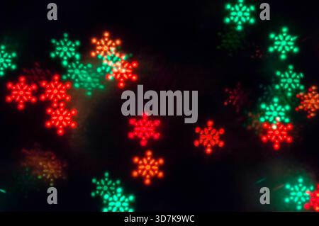 Christmas lights background with blurred Christmas festive multicolor bokeh lights, glowing color lights in form of snowflakes Stock Photo