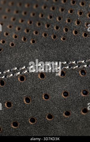 dark smooth perforated leather for shoe , a large number of equal holes in natural leather for shoe production Stock Photo