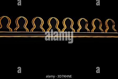 Creative long exposure light painting photography. A horizontal row of glowing yellow curved lines resembling sound waves, audio frequencies, or an or Stock Photo