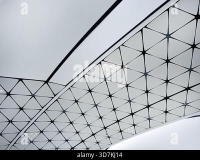 Futuristic building structure. Low angle view of a modern ceiling featuring a repeating triangular geometric pattern. Minimalist white and black grid Stock Photo