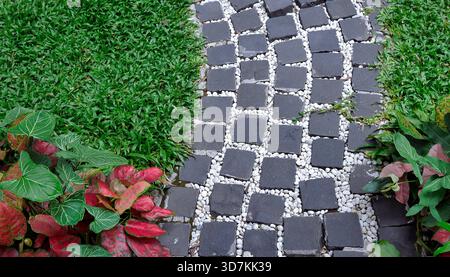 Landscape gardening detail. High angle view of a decorative stone walkway texture. The path is constructed with dark grey granite pavers and white gra Stock Photo