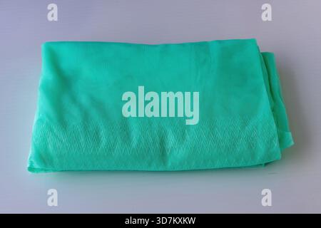 Vibrantly colored, lightweight turquoise mesh mosquito net (bed canopy) folded into a small square on an isolated white background. Health, sleep, tra Stock Photo