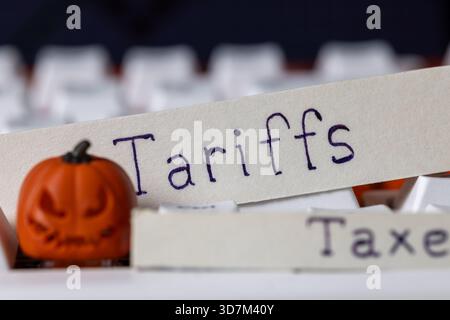 tariffs and taxes written on paper strips with a spooky halloween pumpkin on a white computer keyboard, symbolizing trade policy, international econom Stock Photo
