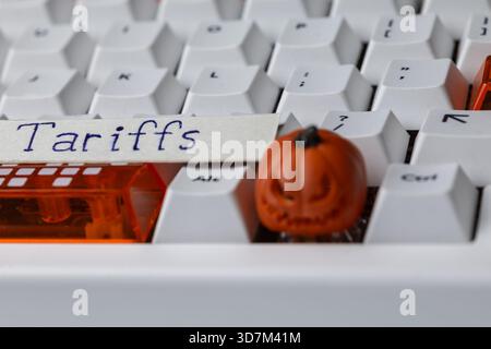 Tariffs concept on a mechanical keyboard with a small, spooky Halloween pumpkin, symbolizing global trade tensions, economic policy, and digital comme Stock Photo