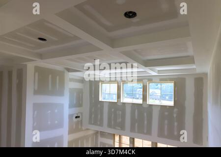 Bright living space with new drywall, coffered ceiling, ample natural light from multiple windows. Stock Photo