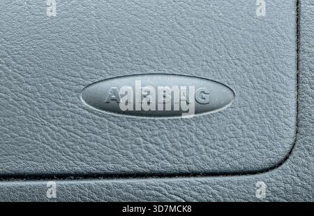 Passenger airbag label on a car dashboard panel, embossed oval symbol on the textured plastic interior, macro closeup detail, safety restraint system Stock Photo