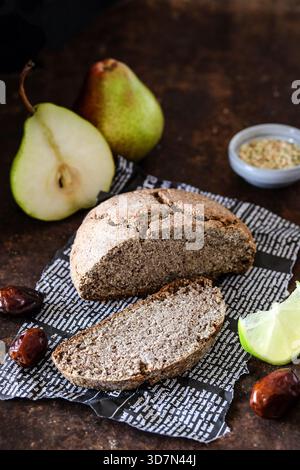 Rustic baked loaf served alongside pears and dates in cozy setting Stock Photo
